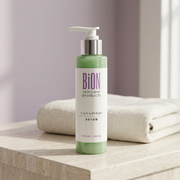 BiON Cucumber Scrub green pump bottle on a pale stone vanity beside ivory towels