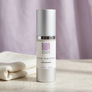 BiON Ultra Moisture Renewal silver bottle on pale stone beside ivory linen with lilac backdrop