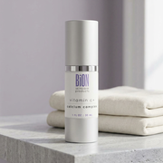 BiON Vitamin C + Calcium Complex silver bottle on pale stone vanity beside folded ivory linen