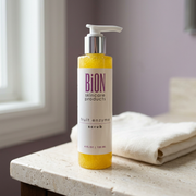 BiON Fruit Enzyme Scrub yellow pump bottle on a pale stone vanity beside ivory linen