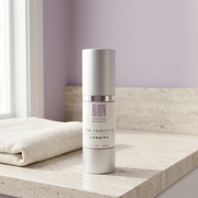 BiON Line Reducing Complex bottle on a pale stone vanity beside ivory linen in soft window light